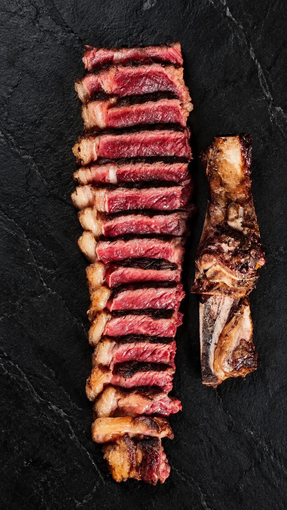 Carne a la parrilla cortada en láminas sobre pizarra